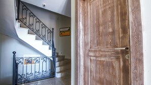 A staircase with a wrought iron railing and a wooden door with a brass handle. - Bakbay Bozcaada (Bozcaada)