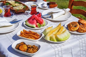 A table set with various dishes including watermelon, fried items, and pastries, suggesting a meal setting. - Bakbay Bozcaada (Bozcaada)