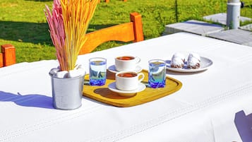 An outdoor dining area with tables and chairs, a white tablecloth, and a view of the surrounding landscape.