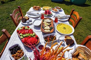 A table set outdoors with various dishes, including bread, salads, and dips. - Bakbay Bozcaada (Bozcaada)