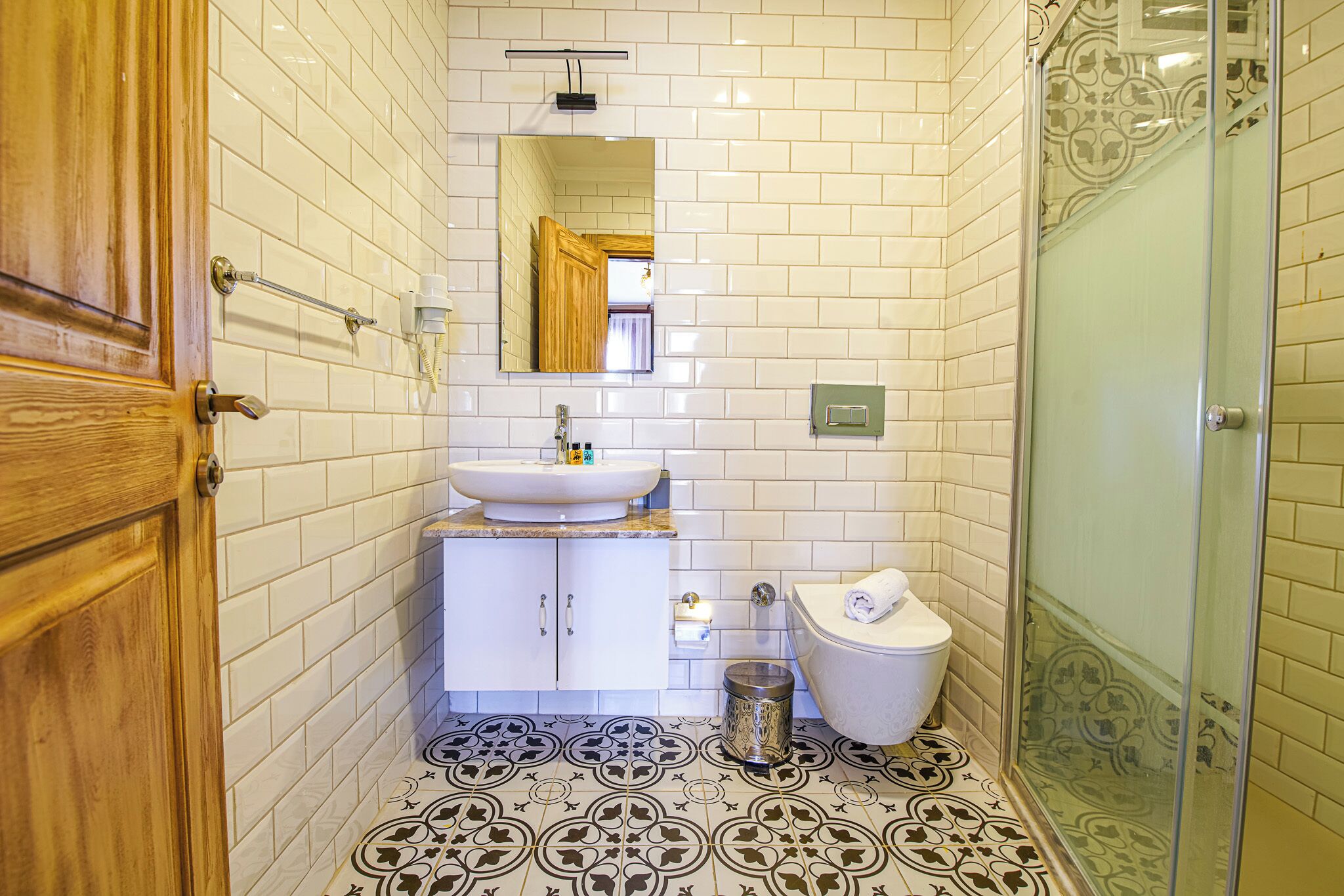 A bathroom with white tiled walls, a sink, a toilet, and a shower.