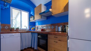A kitchen with a dishwasher, oven, and refrigerator. There is a window with blinds, a microwave, and a sink. - Casa Nora T2 (Castro Marim)