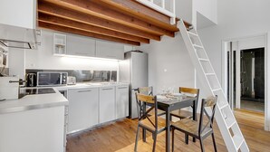 Eine moderne Küche mit weißen Schränken, einer Holzbalkendecke und einem Essbereich mit Tisch und Stühlen.