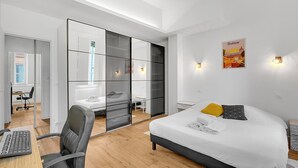 Ein modernes Hotelzimmer mit Bett, Schreibtisch, Stuhl und Spiegel.