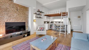 Ein modernes Wohnzimmer mit Backsteinwand, Flachbildfernseher, Couchtisch und blauem Sofa.