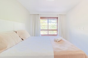 A hotel room with a large bed, a window with curtains, and a view of greenery outside. - PF35 Ótimo Quarto e Sala a 25m da Praia (Mata de São João)