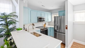 A modern kitchen with light blue cabinets, stainless steel appliances, and a white countertop. - Hot Tub Oasis • Parking • 1 Block to King St! (Charleston)