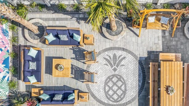 An outdoor patio with multiple seating areas, including sofas, chairs, and a wooden table. - Hot Tub Oasis • Parking • 1 Block to King St! (Charleston)