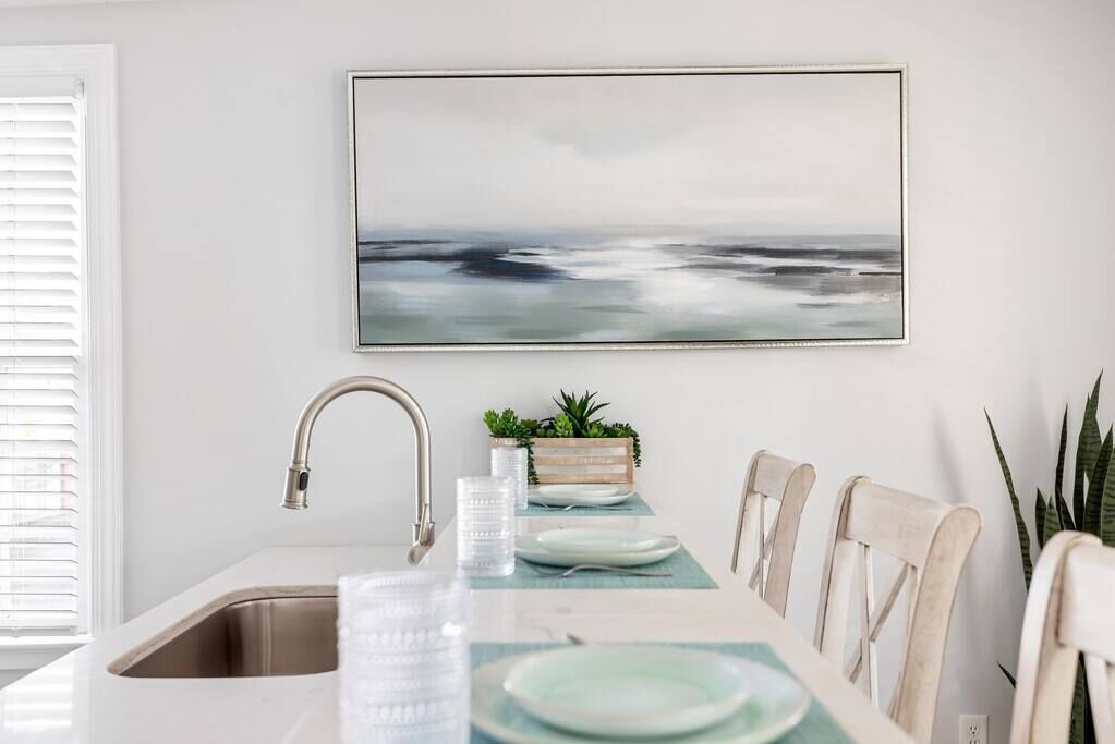 A modern kitchen with a white countertop, stainless steel sink, and a dining area with a table set for two.