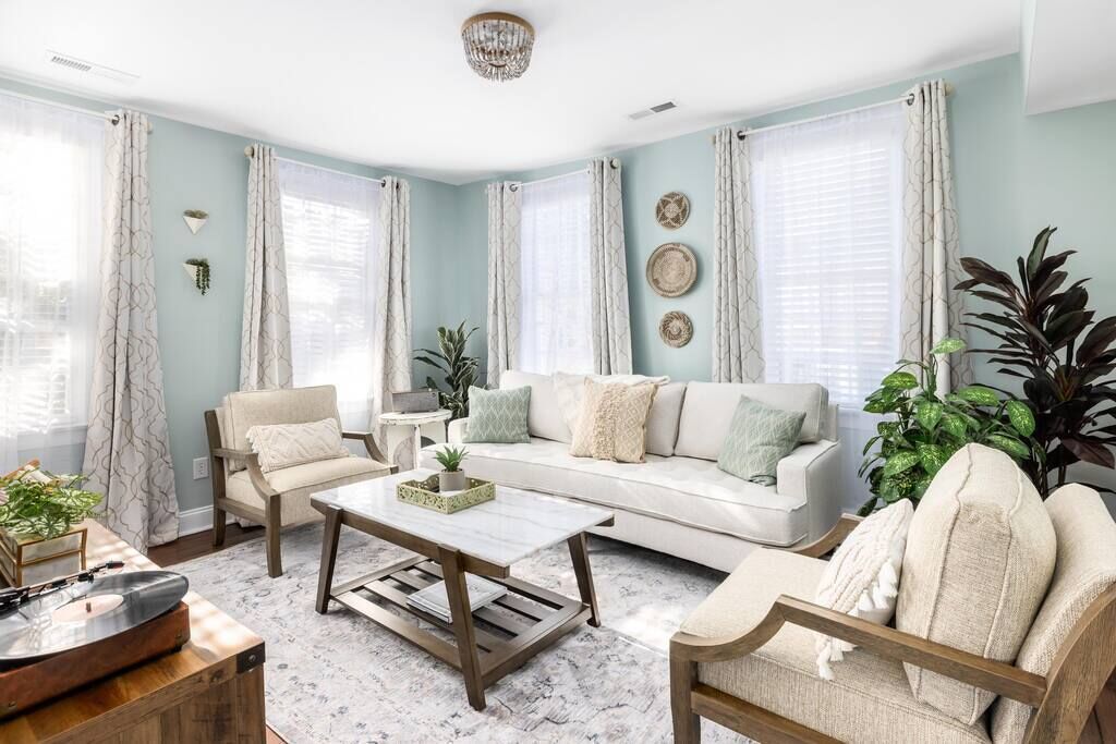 A living room with a white sofa, two armchairs, a coffee table, and a record player.