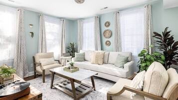 A living room with a white sofa, two armchairs, a coffee table, and a record player.