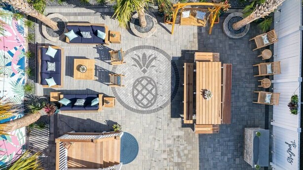 An outdoor patio area with seating arrangements, a central table, and a decorative circular pattern on the floor. - Hot Tub Getaway • Parking • 1 Block to King St! (Charleston)