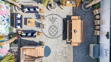 An outdoor patio area with seating arrangements, a central table, and a decorative circular pattern on the floor.