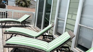 Eine Terrasse mit Korlounge-Stühlen und einer Palme.