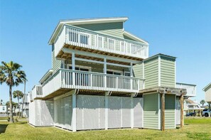 A two-story house with a balcony and a covered porch area. - Family Friendly Seaside Home 2 Blocks from Beach Covered Patio (Galveston)