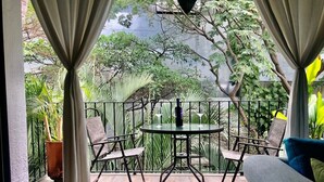A patio with a round table and four chairs, surrounded by a metal fence and potted plants.