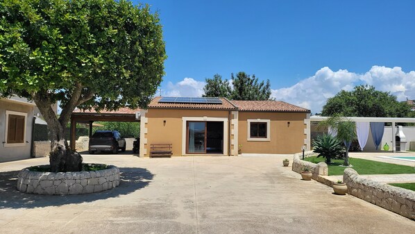 A building with a tiled roof, a covered entrance, and a paved driveway.
