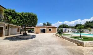 A residential property with a covered driveway, a swimming pool, and a well-maintained lawn.