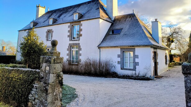 A large, white building with multiple chimneys and a gravel driveway.