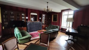A living room with a fireplace, leather sofas, wooden flooring, and a chandelier.