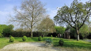 A garden with a gravel path, a metal bench, and a small brick structure.