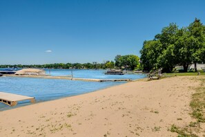 A beach with a dock, a boat, and a clear blue sky.