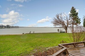 A grassy area with a wooden deck and a view of a lake.