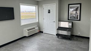 Un baño con ventana, una puerta que indica "Restroom", un aire acondicionado instalado y un refrigerador.