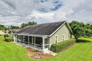 Une maison moderne dotée d’un porche vitré, entourée de pelouses et d’arbres bien entretenus.