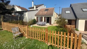 A residential property with a fenced backyard, a covered patio, and a wooden bench. - Quiet gite with garden 300 m from Le Guichet rer station (Orsay)