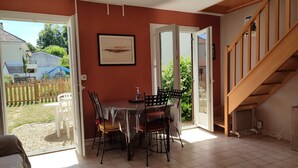 A dining area with a table and chairs, a framed picture on the wall, and a staircase. - Quiet gite with garden 300 m from Le Guichet rer station (Orsay)