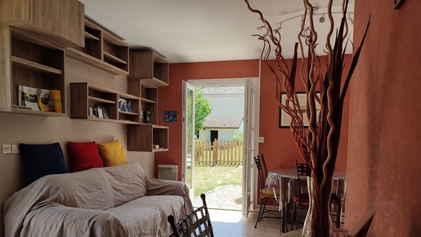 A bedroom with a bed, a table with chairs, a bookshelf, and a view of the outside. - Quiet gite with garden 300 m from Le Guichet rer station (Orsay)