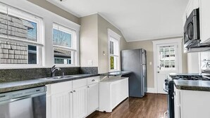 Una cocina moderna con armarios blancos, un refrigerador de acero inoxidable y un horno empotrado.