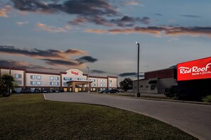 A Red Roof Inn & Suites building with a parking lot, a grassy area, and a clear sky with clouds. - Red Roof Inn & Suites Houma (Houma)