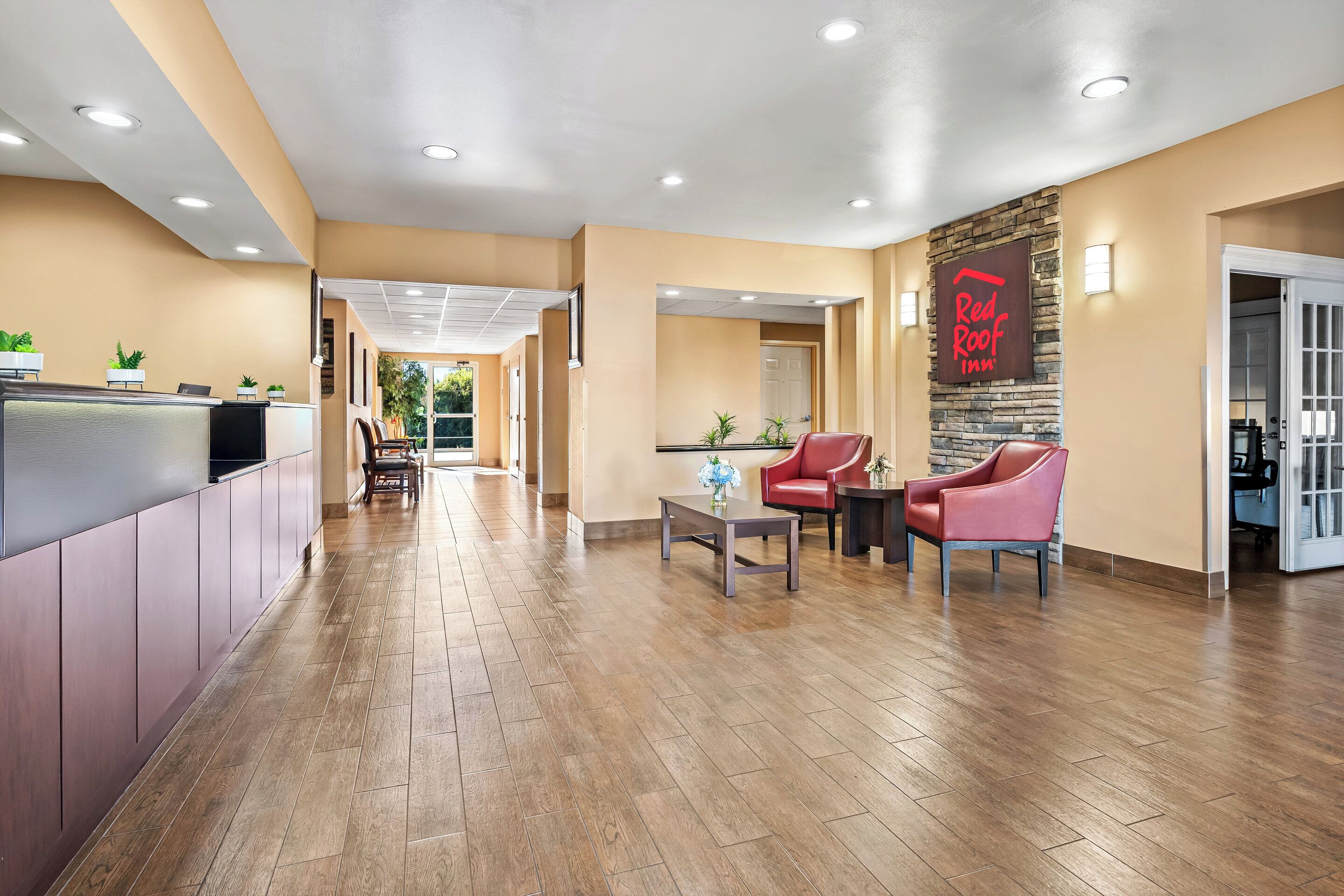 A hotel lobby with a reception desk, seating area, and a Red Roof Inn sign.