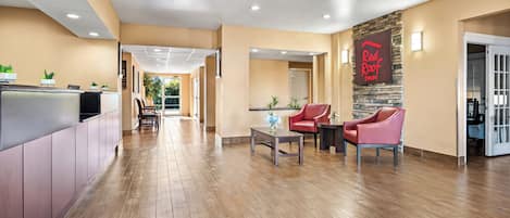A hotel lobby with a reception desk, seating area, and a Red Roof Inn sign.