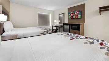 A hotel room with two beds, a desk, a TV, and a large window.