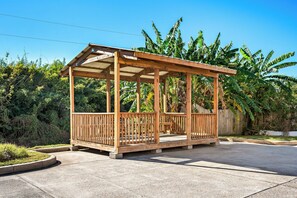 A wooden gazebo with a roof and railings, surrounded by a concrete patio and lush greenery. - Red Roof Inn & Suites Houma (Houma)