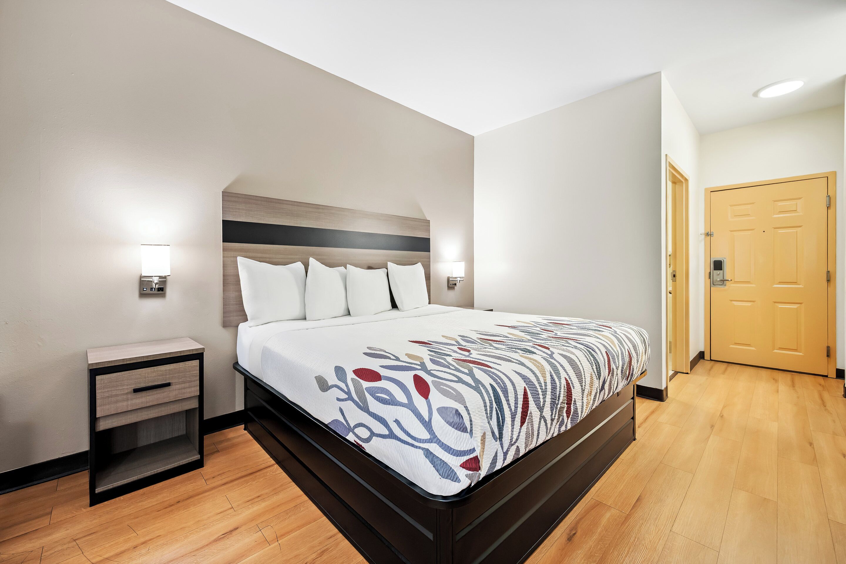 A modern hotel room with a large bed, a bedside table, and a nightstand.
