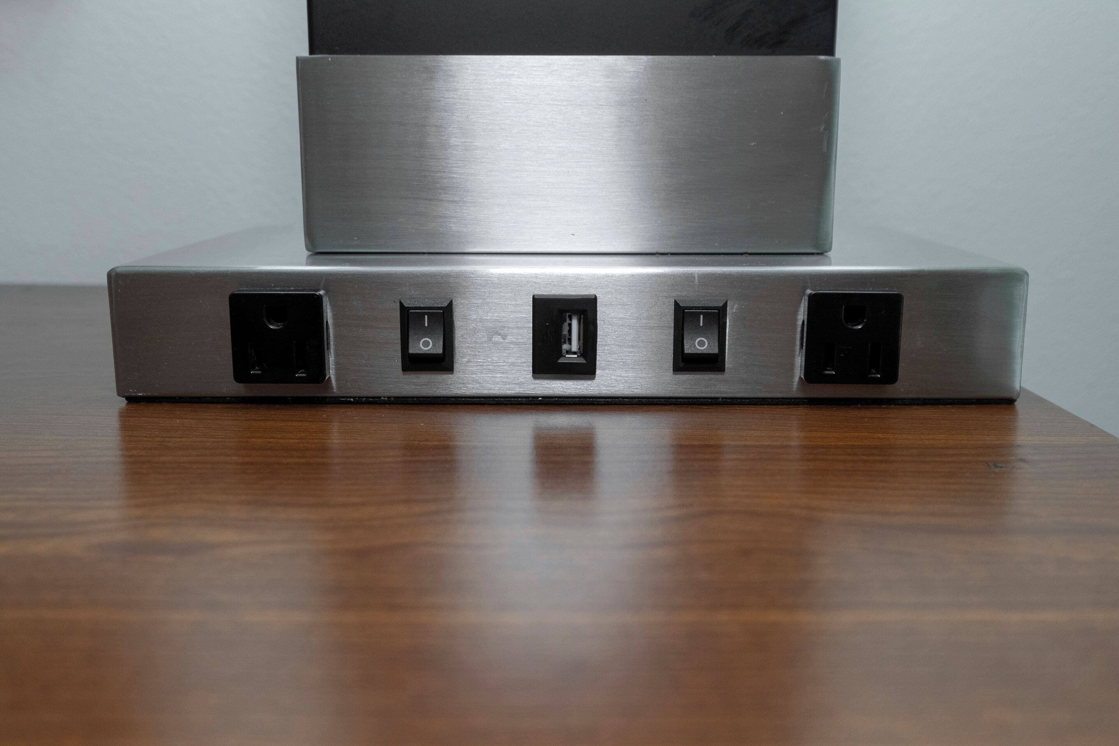 A metallic device with four ports on a wooden surface.