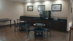 Una cocina con zona de comedor, equipada con refrigerador, cafetera y salpicadero de azulejos.