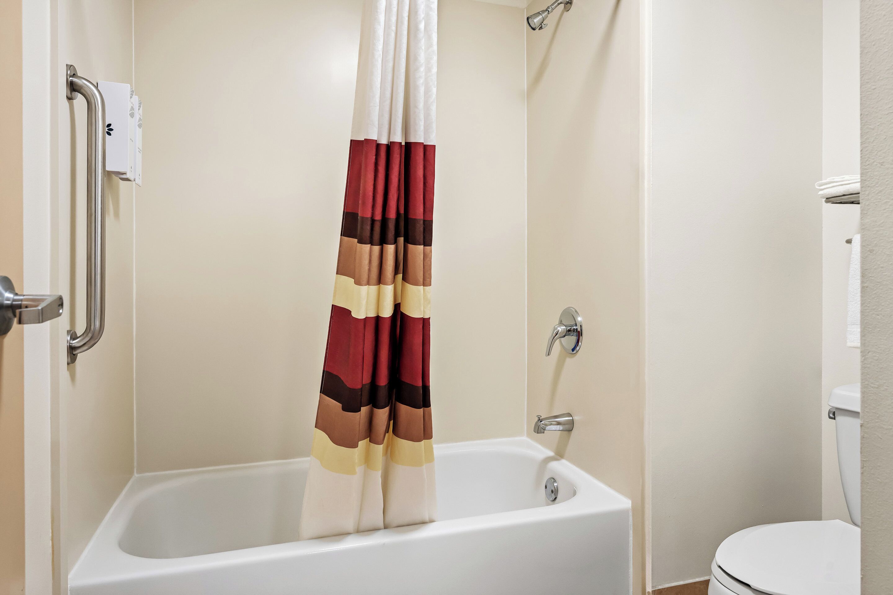 A standard bathroom with a bathtub, a toilet, and a shower curtain.