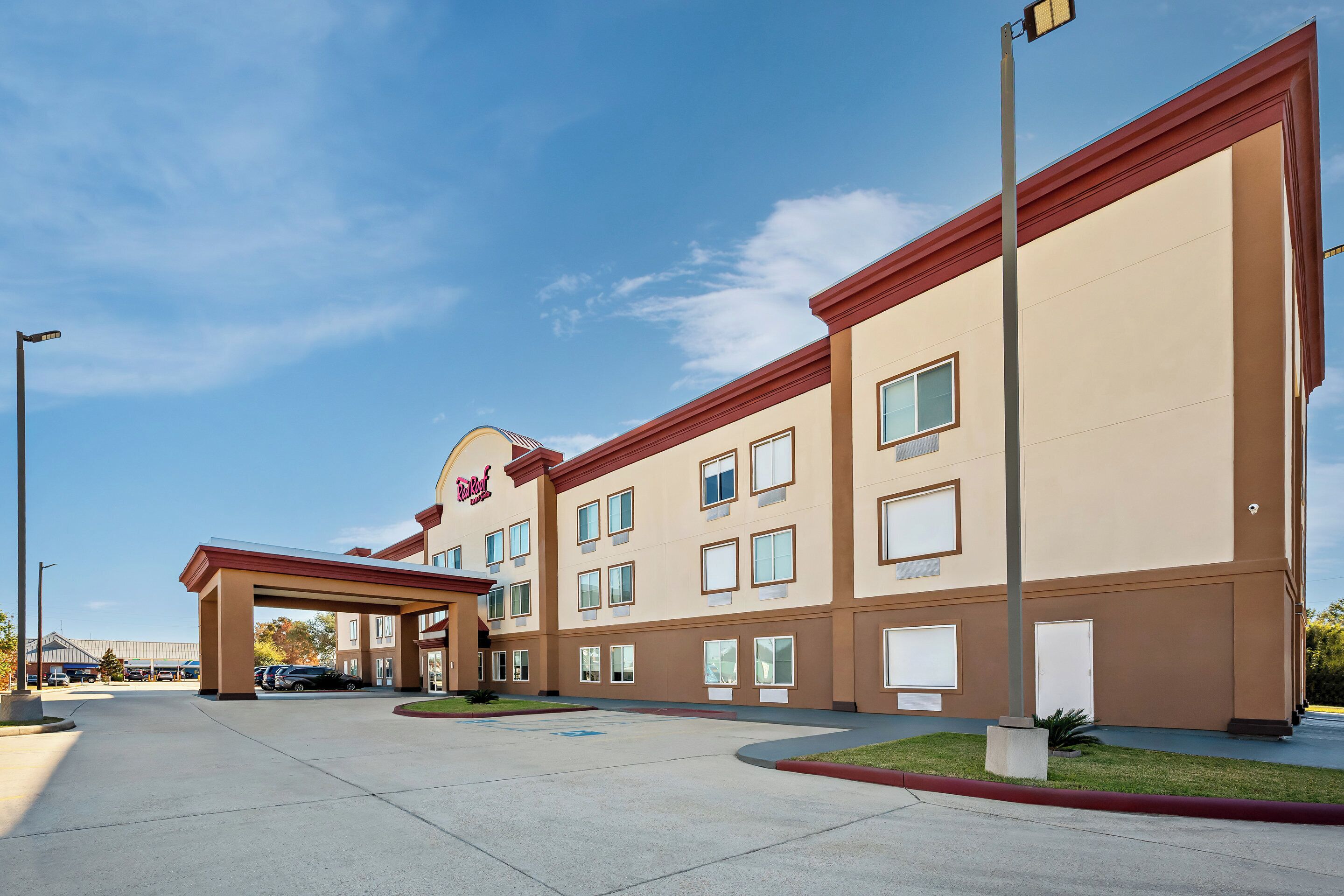 Un hotel con fachada color beige, varias ventanas y un acceso cubierto.