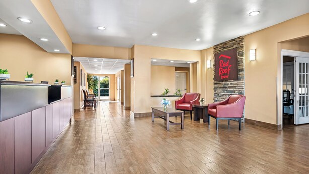 A hotel lobby with a reception desk, seating area, and a Red Roof Inn sign. - Red Roof Inn & Suites Houma (Houma)