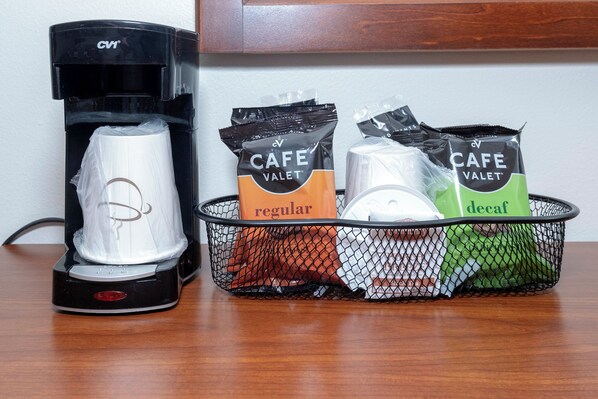 A coffee maker and a basket containing two packets of Cafe Valet coffee, one labeled 'regular' and the other 'decaf'. - Red Roof Inn & Suites Houma (Houma)