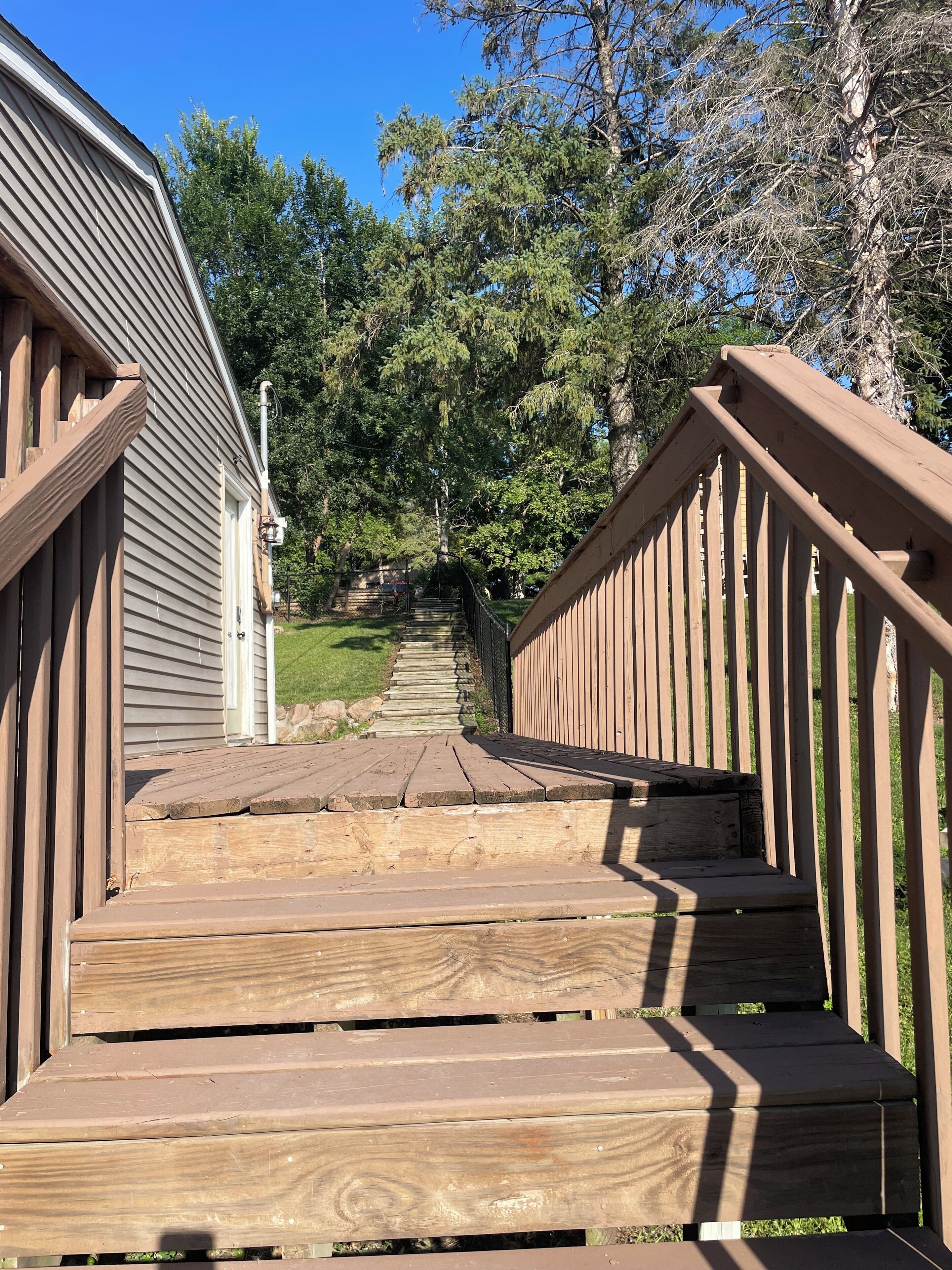 Un escalier en bois mène à une maison dont le toit est en métal.