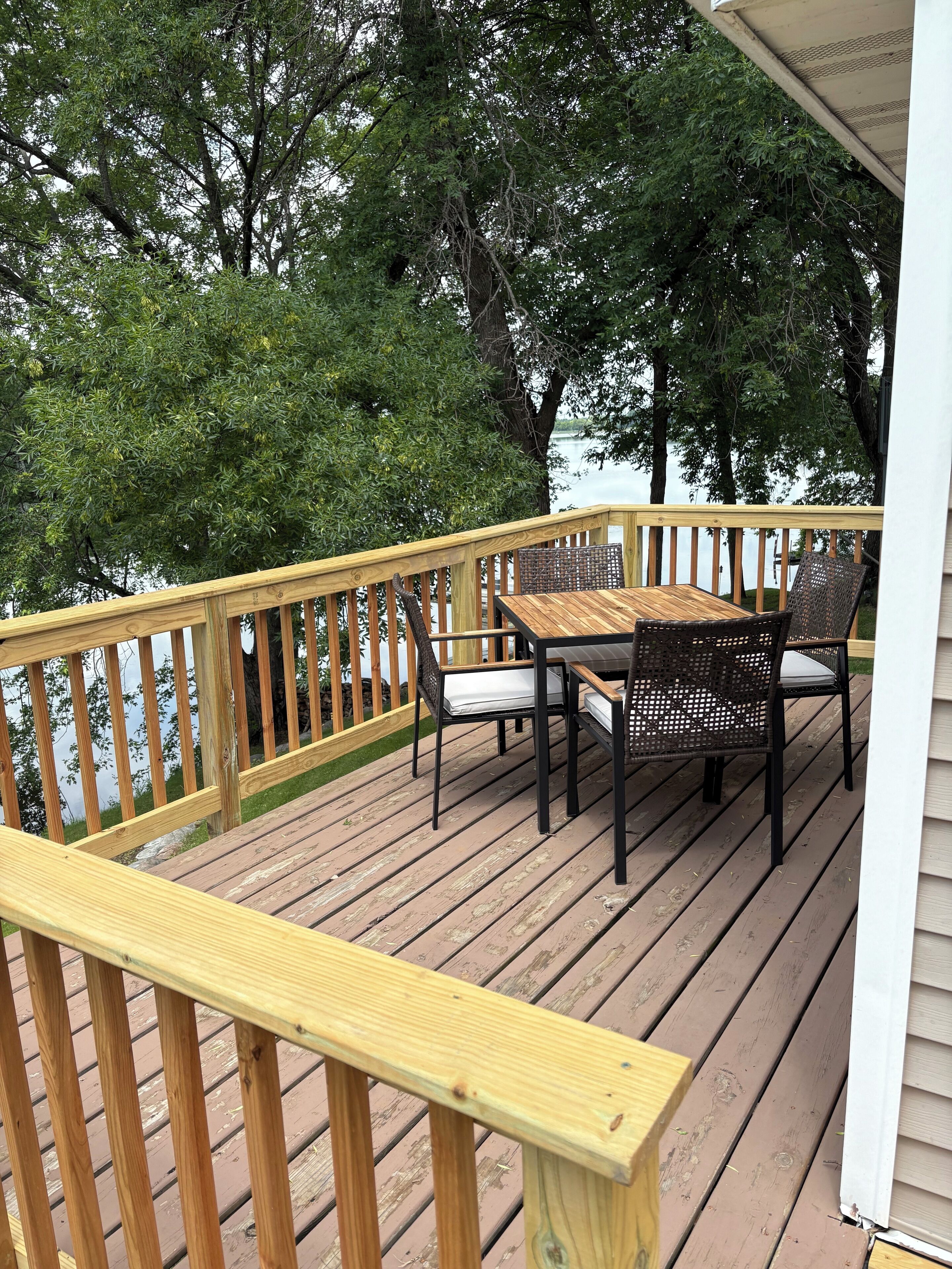 A wooden deck with a table and chairs, overlooking a body of water.