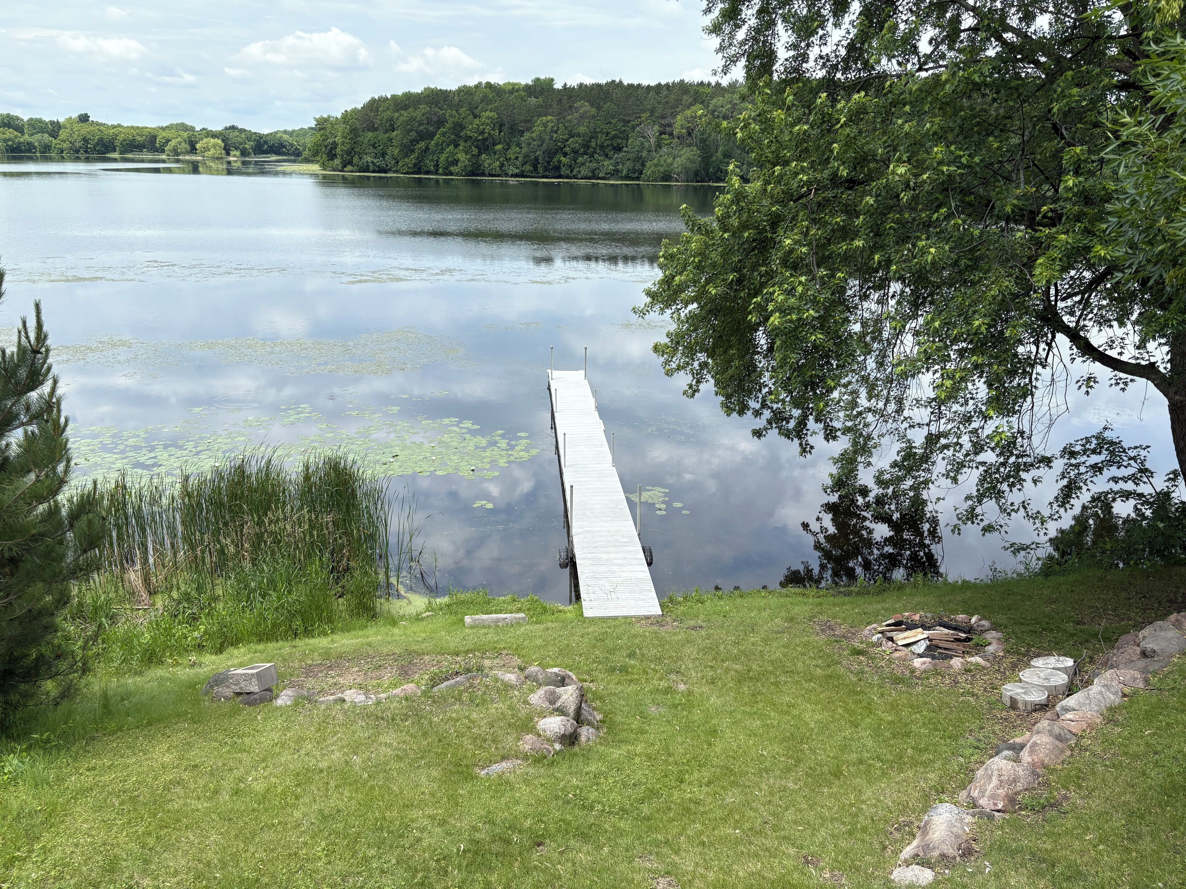 Eine Anlegestelle, die sich in einen stillen See erstreckt, umgeben von üppigem Grün und Bäumen.