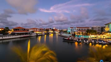 Uma marina com barcos atracados, edifícios à beira-mar e um corpo d'água calma que reflete as construções.