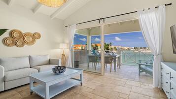 Un balcon avec une table et des chaises, un canapé, un téléviseur et une vue sur la plage.